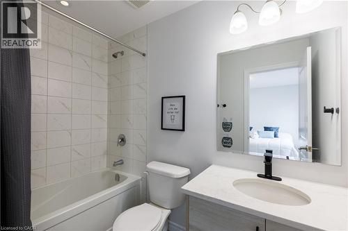 Bathroom with a white tiled shower and tub combination, a toilet, and a vanity featuring a matte black faucet and an oval undermount sink set into a light-toned countertop - 581 Doonwoods Crescent, Kitchener, ON - Indoor Photo Showing Bathroom