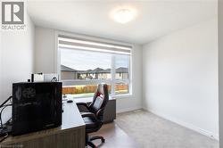 Bright room featuring a large window with roller shades, light grey carpet, white baseboards, and a flush mount ceiling light - 