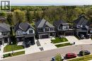 Contemporary residential street featuring multiple homes with dark shingle roofs - 581 Doonwoods Crescent, Kitchener, ON  - Outdoor With Facade 