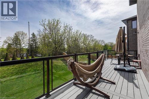 Elevated composite deck featuring a glass panel railing system, brick exterior, and a spacious green lawn - 581 Doonwoods Crescent, Kitchener, ON - Outdoor With Deck Patio Veranda
