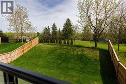 Expansive green lawn with a newly installed wood privacy fence and mature trees - 