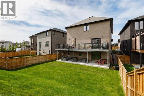 Expansive backyard featuring a manicured lawn, a full wooden privacy fence, and a two-story rear facade - 581 Doonwoods Crescent, Kitchener, ON - Outdoor With Deck Patio Veranda With Exterior