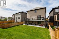 Expansive backyard featuring a manicured lawn, a full wooden privacy fence, and a two-story rear facade - 