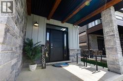 Contemporary exterior with stone facade, vertical siding, a solid black entry door with sidelights, and an overhang featuring exposed wood beams - 