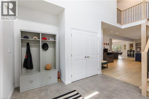 Entryway featuring light gray tile flooring, a built-in storage unit, double panel doors, and a wood-finish staircase with black balusters - 581 Doonwoods Crescent, Kitchener, ON - Indoor Photo Showing Other Room