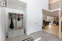 Entryway featuring light gray tile flooring, a built-in storage unit, double panel doors, and a wood-finish staircase with black balusters - 
