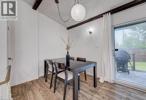 Dining area featuring wood-finish flooring, exposed ceiling beams, and a modern globe pendant light fixture - 128 Pollock Avenue, Cambridge, ON - Indoor Photo Showing Dining Room