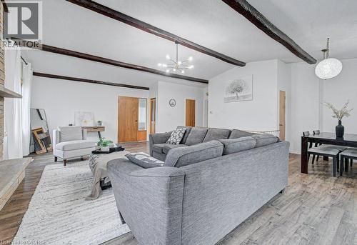 Open concept living space featuring wood-finish flooring, exposed ceiling beams, a stone fireplace, and light wood interior doors - 128 Pollock Avenue, Cambridge, ON - Indoor Photo Showing Living Room
