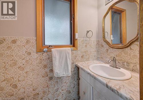Bathroom featuring a white vanity with an oval undermount sink, a stone-finish countertop, and a decorative mirror - 128 Pollock Avenue, Cambridge, ON - Indoor Photo Showing Bathroom