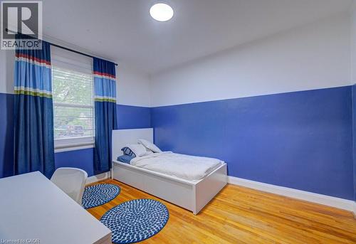 Room featuring wood-finish flooring, a window with blinds, and a built-in ceiling light fixture - 128 Pollock Avenue, Cambridge, ON - Indoor Photo Showing Bedroom