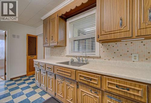 Kitchen featuring wood-finish cabinetry, a stainless steel sink, and a multi-tone mosaic tile backsplash - 128 Pollock Avenue, Cambridge, ON - Indoor Photo Showing Kitchen