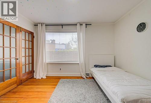 Bright interior space featuring wood-finish flooring, white walls, and crown molding - 128 Pollock Avenue, Cambridge, ON - Indoor Photo Showing Bedroom
