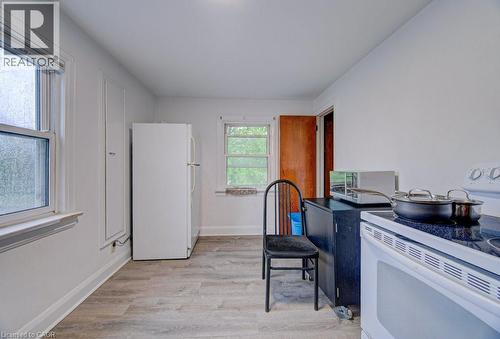 Kitchen space featuring wood-finish flooring and two windows with white trim - 128 Pollock Avenue, Cambridge, ON - Indoor