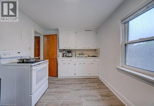 Kitchen featuring white cabinetry, a white electric range, and wood-finish flooring - 128 Pollock Avenue, Cambridge, ON - Indoor Photo Showing Laundry Room