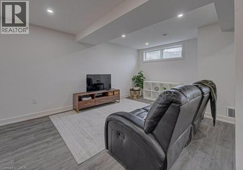Spacious living area featuring wood-finish flooring, recessed lighting, and a white baseboard trim - 128 Pollock Avenue, Cambridge, ON - Indoor