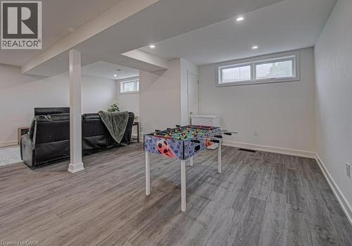 Spacious recreation room featuring wood-finish flooring, recessed lighting, and white baseboards - 128 Pollock Avenue, Cambridge, ON - Indoor