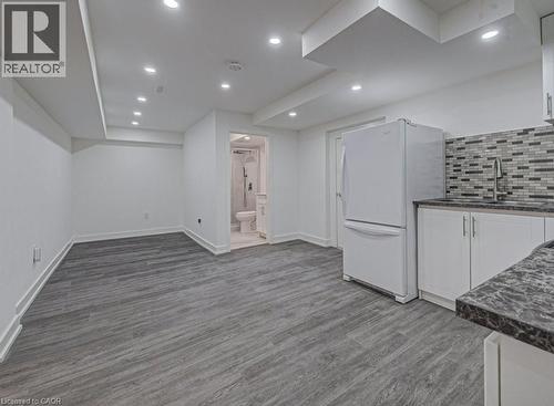 Open-concept living space featuring wood-finish flooring, recessed lighting, and a white appliance package - 128 Pollock Avenue, Cambridge, ON - Indoor