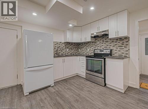 Compact kitchen featuring white cabinetry, a mosaic tile backsplash, stainless steel range, and wood-finish flooring - 128 Pollock Avenue, Cambridge, ON - Indoor Photo Showing Kitchen With Upgraded Kitchen