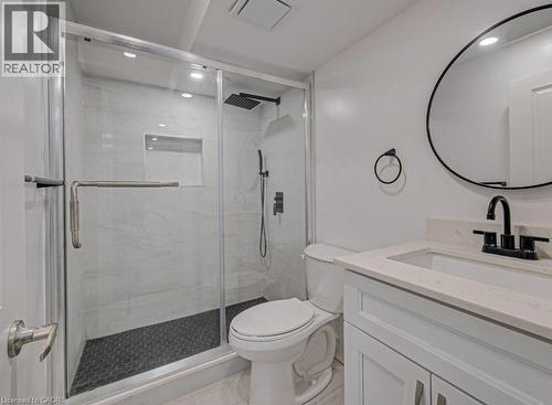 Contemporary bathroom featuring a frameless glass shower enclosure with white tile surround, a dark hexagonal tile shower floor, and a built-in shower niche - 128 Pollock Avenue, Cambridge, ON - Indoor Photo Showing Bathroom