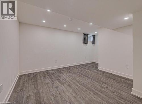 Finished lower-level space featuring contemporary wood-finish flooring, recessed ceiling lighting, and white baseboards - 128 Pollock Avenue, Cambridge, ON - Indoor
