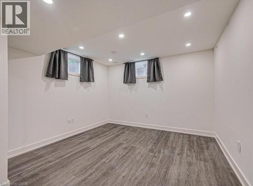 Spacious room featuring wood-finish flooring, white walls, recessed ceiling lighting, and two windows with drapery - 128 Pollock Avenue, Cambridge, ON - Indoor Photo Showing Other Room
