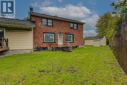 Brick exterior featuring a rear entry door with concrete steps and metal railings - 128 Pollock Avenue, Cambridge, ON - Outdoor With Exterior