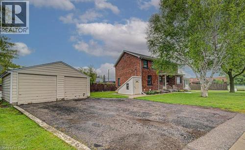 Two-car detached garage with horizontal siding, a gravel driveway, and a mature tree with white bark - 128 Pollock Avenue, Cambridge, ON - Outdoor