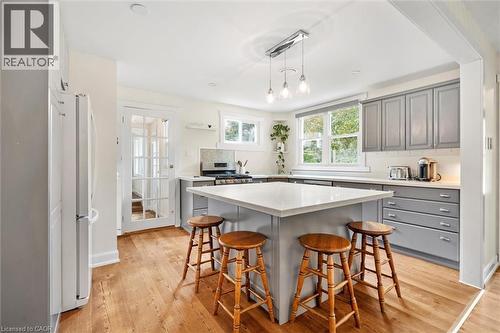 Kitchen featuring a central island with countertop seating, gray cabinetry, light-toned countertops, wood-finish flooring, and a French pane door - 6295 Guelph Line, Burlington, ON - Indoor Photo Showing Kitchen