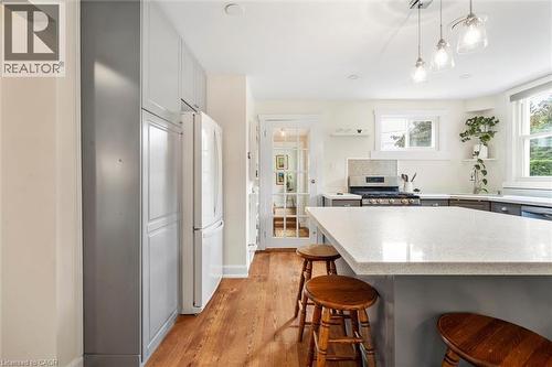 Kitchen featuring an oversized island with a light-toned countertop, wood-finish flooring, recessed lighting, and pendant light fixtures - 6295 Guelph Line, Burlington, ON - Indoor Photo Showing Kitchen