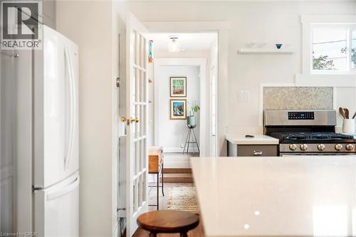 Bright kitchen featuring a white quartz countertop, stainless steel gas range with a mosaic tile backsplash, and white cabinetry - 6295 Guelph Line, Burlington, ON - Indoor