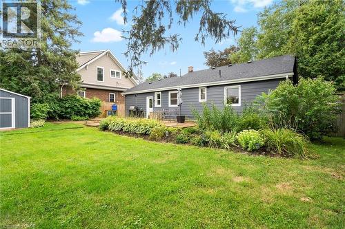 Expansive backyard featuring a manicured lawn, a gray storage shed, a wood deck, and mature landscaping - 6295 Guelph Line, Burlington, ON - Outdoor