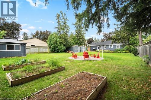 Expansive backyard featuring a manicured lawn, two raised garden beds, a circular paved patio, and two detached storage sheds - 6295 Guelph Line, Burlington, ON - Outdoor With Backyard