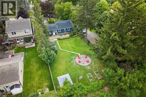 Expansive green lawn featuring a circular fire pit area with seating, raised garden beds, a storage shed, and mature trees providing natural privacy - 6295 Guelph Line, Burlington, ON - Outdoor With View