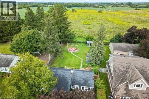 Expansive backyard featuring a manicured lawn, established perimeter fencing, mature trees, a dedicated fire pit area, and a storage shed - 6295 Guelph Line, Burlington, ON - Outdoor With View