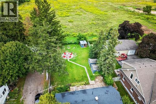 Expansive green space featuring a circular paver patio with a fire pit, mature trees, a detached storage shed, and a paved drive - 6295 Guelph Line, Burlington, ON - Outdoor