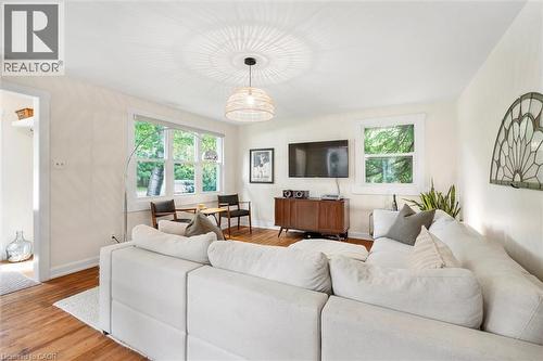 Living area featuring wood-finish flooring, white walls, multiple windows, and a woven pendant light fixture - 6295 Guelph Line, Burlington, ON - Indoor Photo Showing Living Room