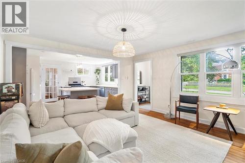 Living room featuring wood-finish flooring, a neutral area rug, and multiple large windows with roller shades - 6295 Guelph Line, Burlington, ON - Indoor Photo Showing Living Room