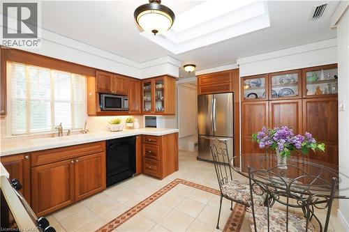Kitchen featuring warm wood cabinetry, light-toned countertops, a stainless steel refrigerator, and integrated appliances - 2023 Coronation Boulevard, Cambridge, ON - Indoor Photo Showing Kitchen