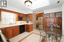 Kitchen featuring warm wood cabinetry, light-toned countertops, a stainless steel refrigerator, and integrated appliances - 