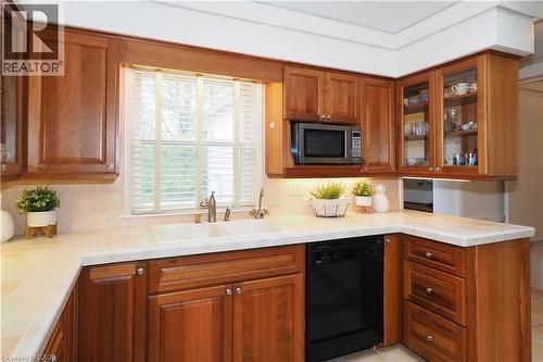 Kitchen featuring wood cabinetry, light-toned countertops, a double basin sink with a brushed nickel faucet, a built-in microwave, and an integrated dishwasher - 2023 Coronation Boulevard, Cambridge, ON - Indoor Photo Showing Kitchen With Double Sink