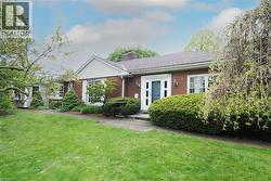 Brick exterior featuring white trim accents, a prominent front entry with sidelights, and a pitched roofline - 