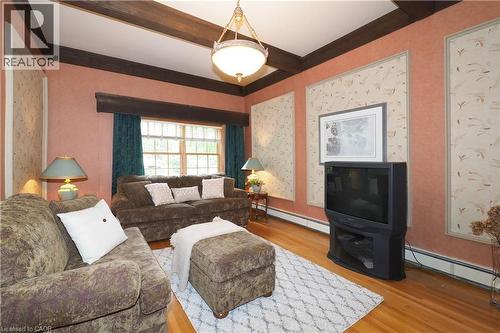 Living area featuring exposed ceiling beams, wood-finish flooring, a multi-pane window, and wall panels with decorative trim - 2023 Coronation Boulevard, Cambridge, ON - Indoor Photo Showing Living Room