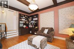 Room featuring corner built-in shelving, wood-finish flooring, exposed ceiling beams, and a semi-flush mount light fixture - 