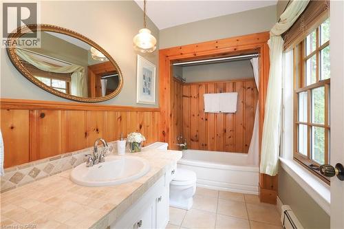 Bathroom featuring wood-paneled walls, a tile countertop with an integrated sink, and an oval mirror - 2023 Coronation Boulevard, Cambridge, ON - Indoor Photo Showing Bathroom