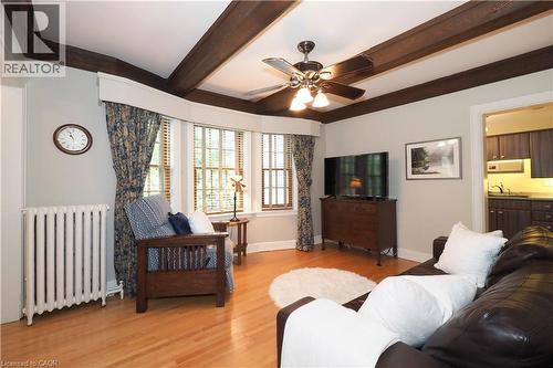 Living area featuring wood-finish flooring, exposed ceiling beams, a bay window with natural light, a ceiling fan, and a radiator - 2023 Coronation Boulevard, Cambridge, ON - Indoor Photo Showing Living Room