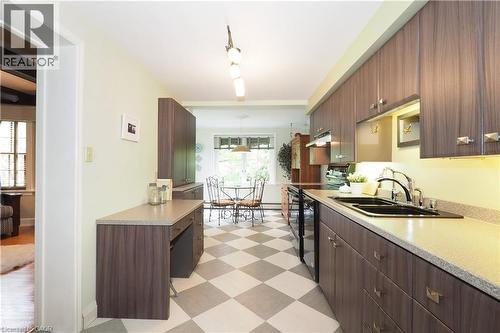 Galley kitchen featuring wood-finish cabinetry, light-toned countertops, and a checkered floor pattern - 2023 Coronation Boulevard, Cambridge, ON - Indoor Photo Showing Kitchen With Double Sink