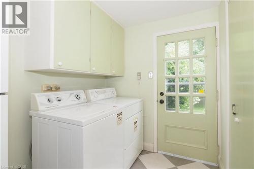 Dedicated laundry area featuring overhead cabinetry, a paneled exterior door with multiple glass lites, and checkerboard floor tiles - 2023 Coronation Boulevard, Cambridge, ON - Indoor Photo Showing Laundry Room
