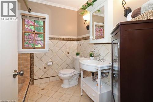 Bathroom featuring decorative tile work, a pedestal sink with chrome fixtures, and a wood-framed window - 2023 Coronation Boulevard, Cambridge, ON - Indoor Photo Showing Bathroom