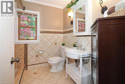 Bathroom featuring decorative tile work, a pedestal sink with chrome fixtures, and a wood-framed window - 