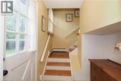 Entryway featuring a white paneled door with glass inserts, wood-finish stairs with white risers and railing, and a window with horizontal blinds - 2023 Coronation Boulevard, Cambridge, ON - Indoor Photo Showing Other Room